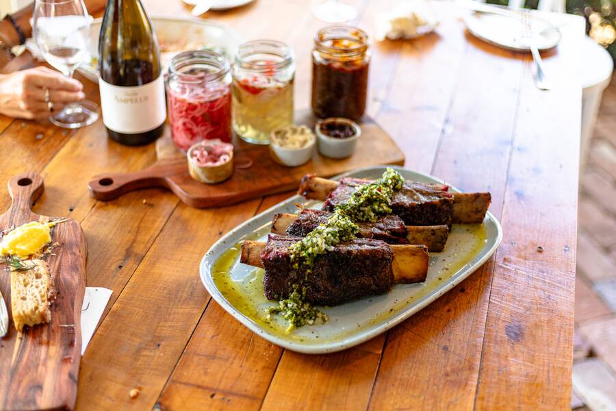 A table set with short ribs, wine and preserves for the Smokey Sunday Parilla